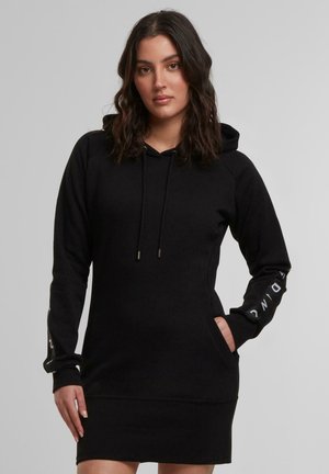 Zwart hoodie-dress met een voorketen, capuchon met trekkoord en lange mouwen. Bevat tekst op de mouwen en heeft een slim fit ontwerp. Soepele textuur.