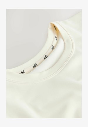 Koszulka w kolorze kremowym, z krótkim rękawem i zaokrąglonym dekoltem. Miękki materiał o gładkiej fakturze. Metka wewnątrz kołnierza z napisem "self".