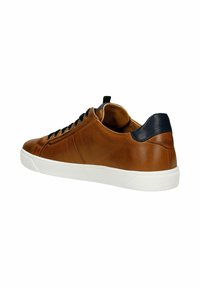 Hnědé kožené tenisky s bílou podrážkou, černými tkaničkami a námořnickým akcentem na patě. Mají hladkou texturu a minimalistický design s bočním švem.
