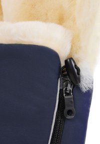 Marineblauwe textielen laars met een fluffy crèmekleurige voering, voorzien van een rits met een zwarte trekker en zilveren hardware. Gevoelig oppervlak zichtbaar.