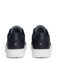Granatowe skórzane trampki z teksturowanym materiałem, białą gumową podeszwą i małą metką z logo z tyłu. Niskoprofilowy design z wyściełanym obcasem.