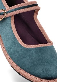 Bailarina de ante color teal con ribete rosa y una hebilla decorativa. Presenta un forro suave y oscuro, y una puntera redondeada, que realza la comodidad y el estilo.