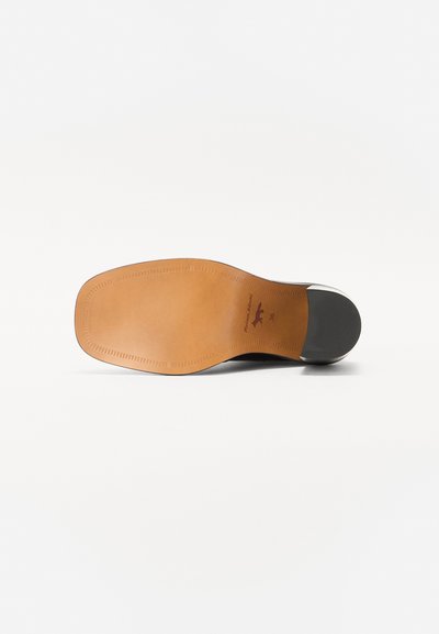 Suela de zapato con una superficie de cuero marrón liso, punta redondeada y tacón de goma negra. Incluye costuras alrededor del perímetro y un sello de la marca.