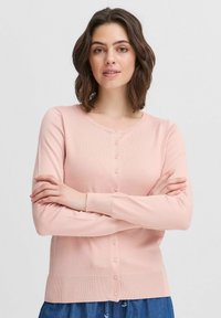 Cardigan rosa chiaro realizzato in materiale morbido, con scollatura rotonda, chiusura a bottoni e maniche lunghe. Tessuto liscio con orlo a costine.