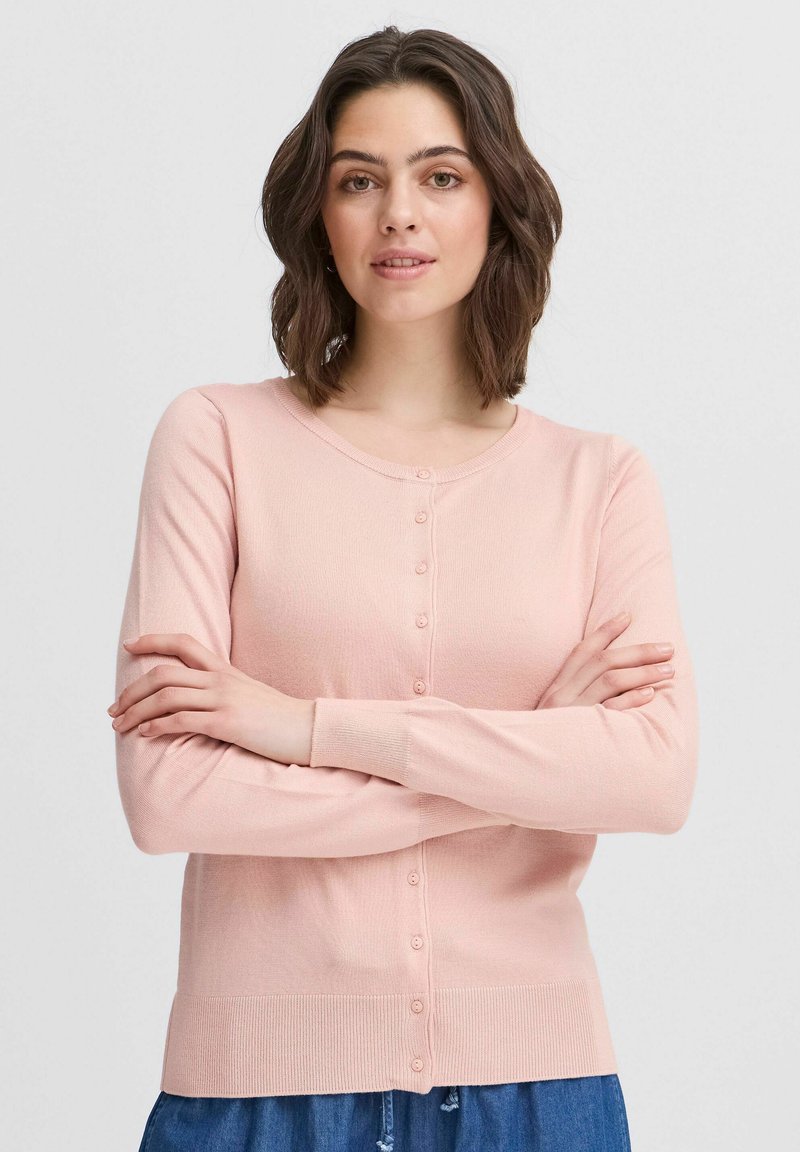 Cardigan rosa chiaro realizzato in materiale morbido, con scollatura rotonda, chiusura a bottoni e maniche lunghe. Tessuto liscio con orlo a costine.