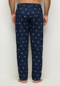 Pantalones de pijama en color navy con cintura elástica, con un patrón repetido de pequeños perros en color naranja y blanco. Tejido ligero, corte relajado.