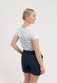 Hvit T-skjorte med marineblå striper på baksiden, parret med marineblå shorts. Glatt stoff, avslappet passform, kortermet og rund hals.