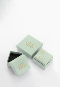 Mintgrøn papgaveæsker med guldtryk logo, én hexagonal og to firkantede, der har teksturerede overflader og aftagelige låg.
