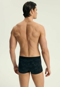 Czarne bokserki z fakturowanym wzorem, o dopasowanym kroju, z elastycznym pasem i gładkim materiałem. Model pokazany z tyłu.