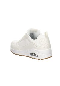 Sneaker de sport blanc avec une tige en synthétique lisse, un col rembourré, un design à lacets, des détails perforés et une semelle en caoutchouc avec un amorti à air.