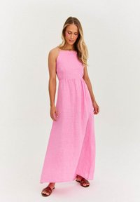 Różowa lniana sukienka maxi z kwadratowym dekoltem, cienkimi ramiączkami i marszczonym wcięciem w talii, w połączeniu z brązowymi klapkami, na neutralnym tle.