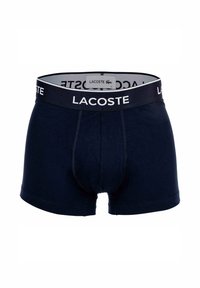Boxer in cotone blu navy con design aderente, caratterizzati da una vita in contrasto con il logo "LACOSTE" bianco e un'etichetta all'interno.
