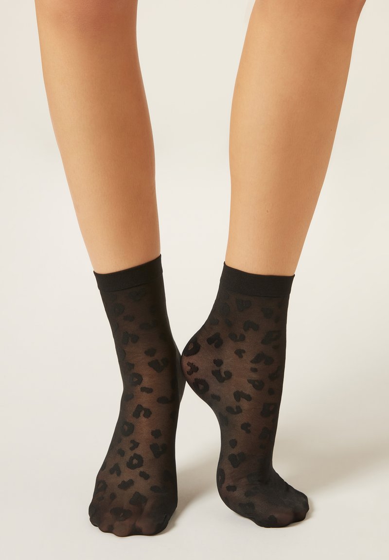 Černé průhledné ponožky s leopardím vzorem, s jednobarevným černým lemem nahoře. Hladká textura a délka po kotníky.