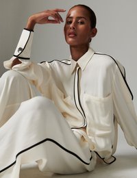 Κρεμ μεταξωτό πουκάμισο και παντελόνια με φαρδιά μπατζάκια και μαύρα περιγράμματα. Διαθέτει τσέπη, εξαιρετικά φαρδιά εφαρμογή και λείο ύφασμα. Κομψός σχεδιασμός.