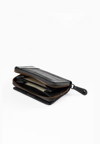 Portafoglio in pelle nera con chiusura a zip, dotato di un interno con scomparti per carte e una fodera in tessuto a righe. Accentuato da cuciture arancioni.