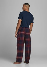 Camiseta de marina de manga corta y pantalones de pijama de cuadros en rojo oscuro, amarillo y marino. Corte holgado, cinturilla elástica y piernas rectas.