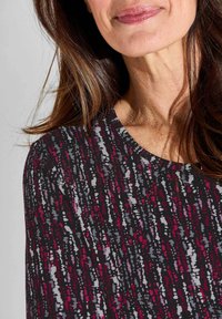 Bunt gefärbtes, strukturiertes Oberteil mit Rundhalsausschnitt und einem Muster aus schwarzen, grauen, pinken und weißen Streifen. Weicher Stoff mit lockerer Passform.