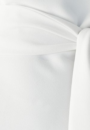 Witte stof met een gladde textuur, met een gedrapeerd ontwerp en een strikdetail in de taille. Een subtiele glans benadrukt de plooien.