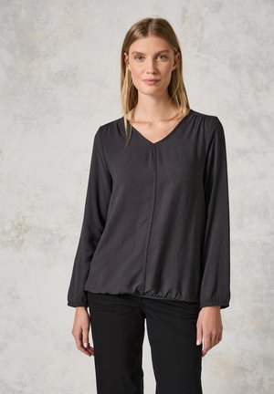 Zwarte blouse met lange mouwen en een V-hals, lichtjes geraffineerde schouders en een elastische zoom. Zachte, gestructureerde stof met subtiele patroondetails.