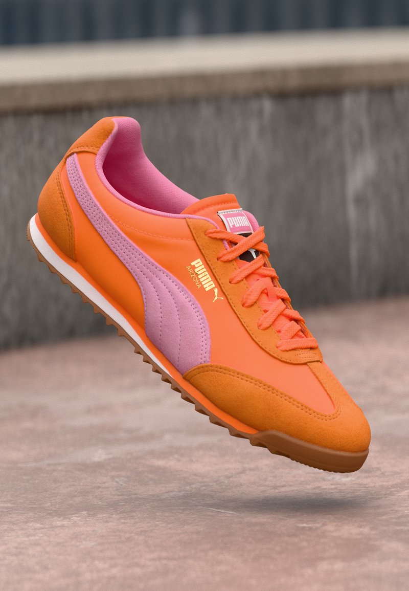 Orange und rosa Puma Sneaker mit glatter Textur, schnüren an der Vorderseite und Gummisohle. Mit einem auffälligen Logo auf der Zunge und seitlichen Streifen.