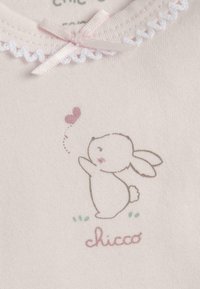 Tissu rose clair avec une texture douce. Présente un lapin de dessin animé et un cœur dans des couleurs pastel. Bordure décorative en dentelle blanche et accent de nœud rose.