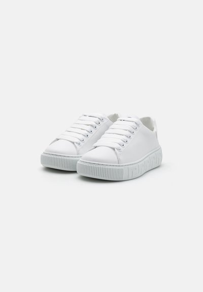 Vita sneakers med ovandel i slätt läder, rund tå och platta vita snören. Har en strukturerad gummisula med vertikala ribbor.