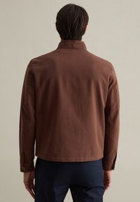 Braune Baumwolljacke mit Kragen, langenÄrmeln und geradem Schnitt, mit einem sauberen Rücken und Knopfmanschetten.