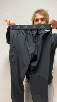 Pantaloni atletici negri din material ușor, cu talie elastică ce prezintă un model repetat cu logo și un design elegant, mulat.