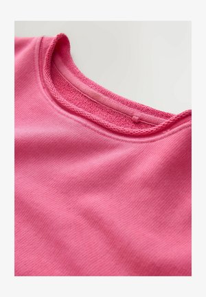 Pink cotton T-shirt with a ribbed crew neckline, featuring a textured neckband and smooth fabric with subtle stretch. No visible patterns.