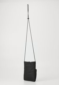 Svart stoff crossover-veske med glidelås, flat form, justerbar stropp og minimalistisk design. Glatt tekstur, kompakt størrelse.