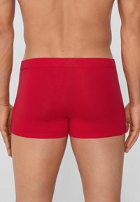 Red stretch fabric boxers with a smooth finish, low-rise waistband, and snug fit, featuring no visible seams or accents.