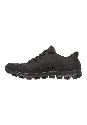 Schwarzer flacher Sportschuh aus gestepptem Stoff, Schnürverschluss und gepolsterte Sohle mit mehreren Aussparungen für Atmungsaktivität.
