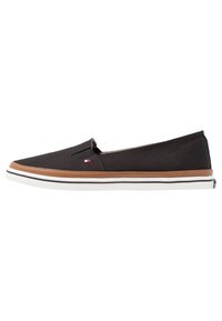 Sneaker nera slip-on con rifiniture marroni e suola bianca, caratterizzata da un piccolo logo rosso, bianco e blu sul lato.