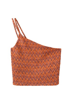 Jeune femme aux longs cheveux blonds portant un crop top orange à motif une épaule et un jean denim bleu clair sur un fond uni.