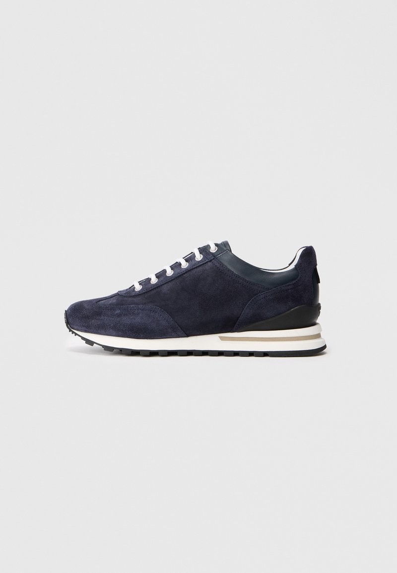 Baskets en suede marine avec lacets blancs et un talon noir contrastant. Présentent une semelle en caoutchouc texturé et un design minimaliste.