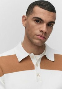 Randig polo skjorta med vita och tan horisontella ränder, med krage, knappstängning och texturerad tyg.