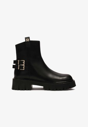 Czarny skórzany botek za kostkę z masywną platformą, dwoma klamrami po boku oraz pętelką z tyłu. Gładka tekstura i elegancki design.