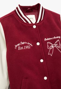 Bordeaux varsityjakke med hvide læderærmer, der har broderet tekst og en sløjfe-design. Afsluttet med hvide trykknapper og en ribbet krave.