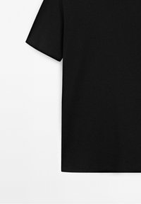 T-shirt noir en coton à manches courtes, vu de face avec une coupe droite et une coupe standard sur fond blanc.