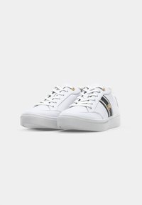Zapatillas blancas con una parte superior suave de material sintético, que cuentan con una franja de acento en negro y dorado y un cierre con cordones. Suela plana de goma.
