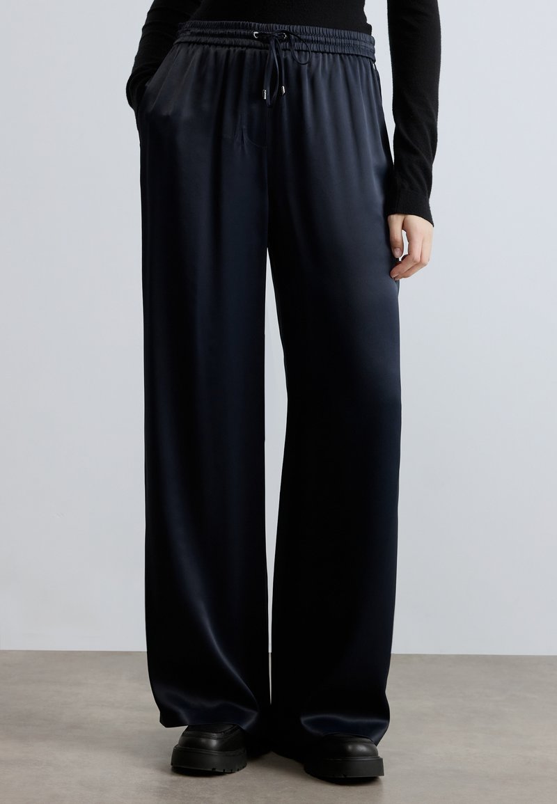 Plati piegriezuma bikses tumši zili zīda izskatā, ar elastīgu jostu, auklu un sānu kabatām. Gluda tekstūra ar maigu spīdumu.