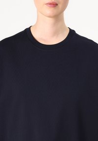 Tumed sinine puuvillane crewneck t-särk sujuva tekstuuriga, millel on lihtne disain ja puuduvad nähtavad mustrid või riistvara.