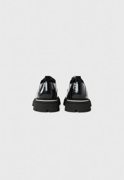 Chaussures en cuir verni noir avec une semelle épaisse, dotées d'un profil en caoutchouc, d'une languette à l'arrière et d'un design élégant. La vue arrière met en avant les détails de couture.