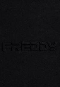 Tessuto nero con un logo "FREDDY" in rilievo e tonale al centro. Il materiale appare liscio con una sottile texture.