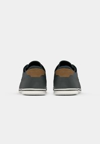 Sneakers neri con dettagli in pelle marrone, forma arrotondata, superficie liscia, suole in gomma bianca e dettagli di cucitura a contrasto nel tallone.