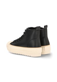 Un par de zapatillas negras de caña alta con suelas de goma beige gruesas y puntas reforzadas, mostradas desde la parte trasera y lateral sobre un fondo blanco.