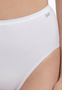 Slip in cotone bianco con una superficie liscia, vita alta e vita elasticizzata. Presenta un piccolo etichetta con il marchio sul lato.