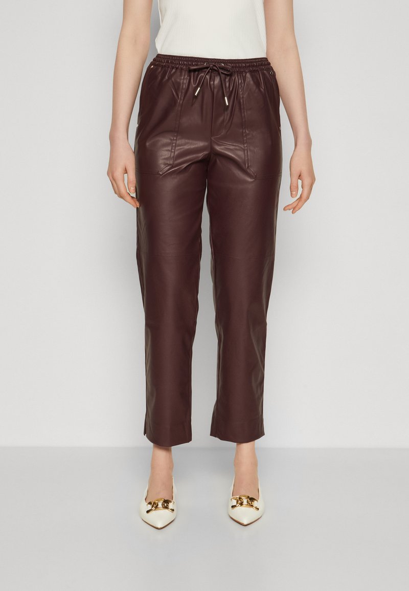 Pantalons courts en cuir bourgogne avec taille élastique et cordon de serrage. Dotés de poches avant et d'une texture lisse. Assortis à des chaussures blanches à bout pointu.