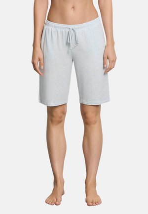 Femme portant un short gris clair mi-cuisses à taille élastique avec cordon, debout pieds nus sur un fond uni.