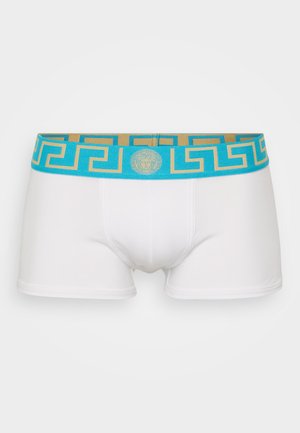 White boxer briefs featuring a turquoise and gold patterned waistband with a Greek key design and a circular logo in the center.